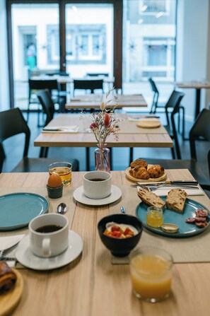Ein Frühstückstisch für zwei Personen, gedeckt mit Croissants, Brot, Kaffee und Saft.
