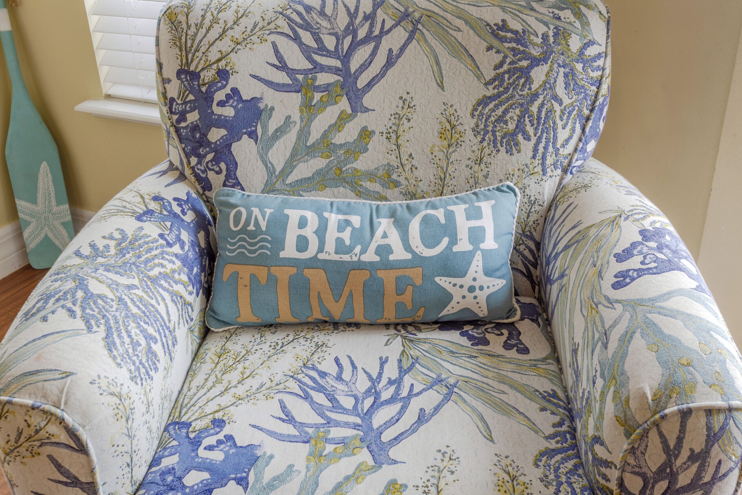 A chair with a cushion featuring a beach theme, including text that reads "ON BEACH TIME."