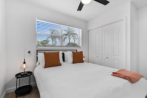Relax in a serene space with a large bed, geometric lamp, and ceiling fan.