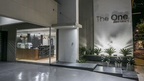 Una entrada de hotel moderna con un mostrador de recepción, puertas de cristal y un gran letrero que dice "The One Downtown".