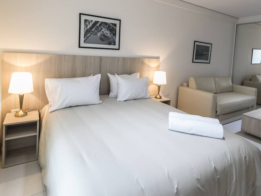 Une chambre d’hôtel avec un grand lit, deux tables de chevet avec des lampes, un canapé et un fauteuil.