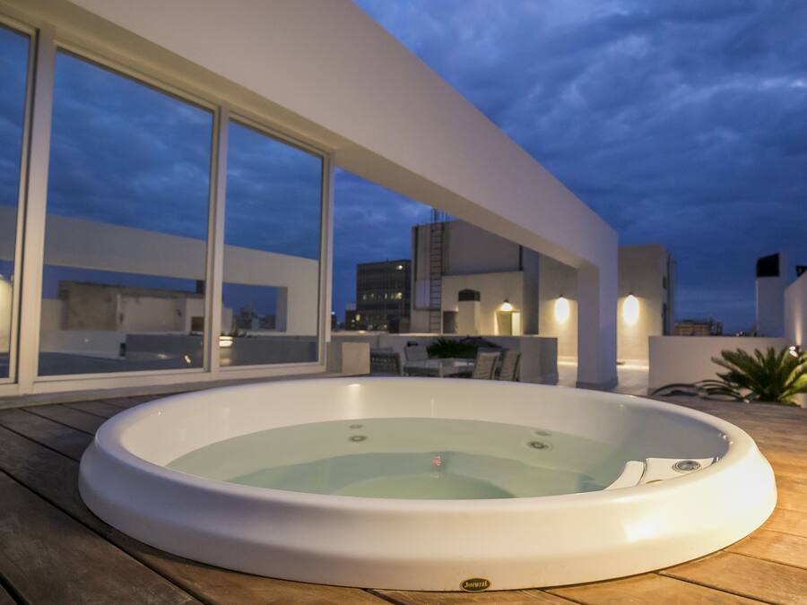 Un jacuzzi en una terraza de madera con vista a la ciudad.