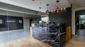 Una moderna zona de recepción con mostrador de mármol, suelo de madera e iluminación colgante.