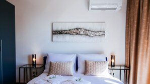 A hotel room with a large bed, two bedside tables, a wall-mounted air conditioner, and a painting above the bed. - Villa Sonik (Zadar)