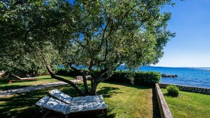 A sun lounger under a tree by a poolside, with a clear view of the sea and a stone wall in the background. - Villa Sonik (Zadar)