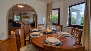 A dining area with a round table set for four, surrounded by wooden chairs. - Villa Sonik (Zadar)