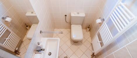 A bathroom with two toilets, a sink, and a shower.
