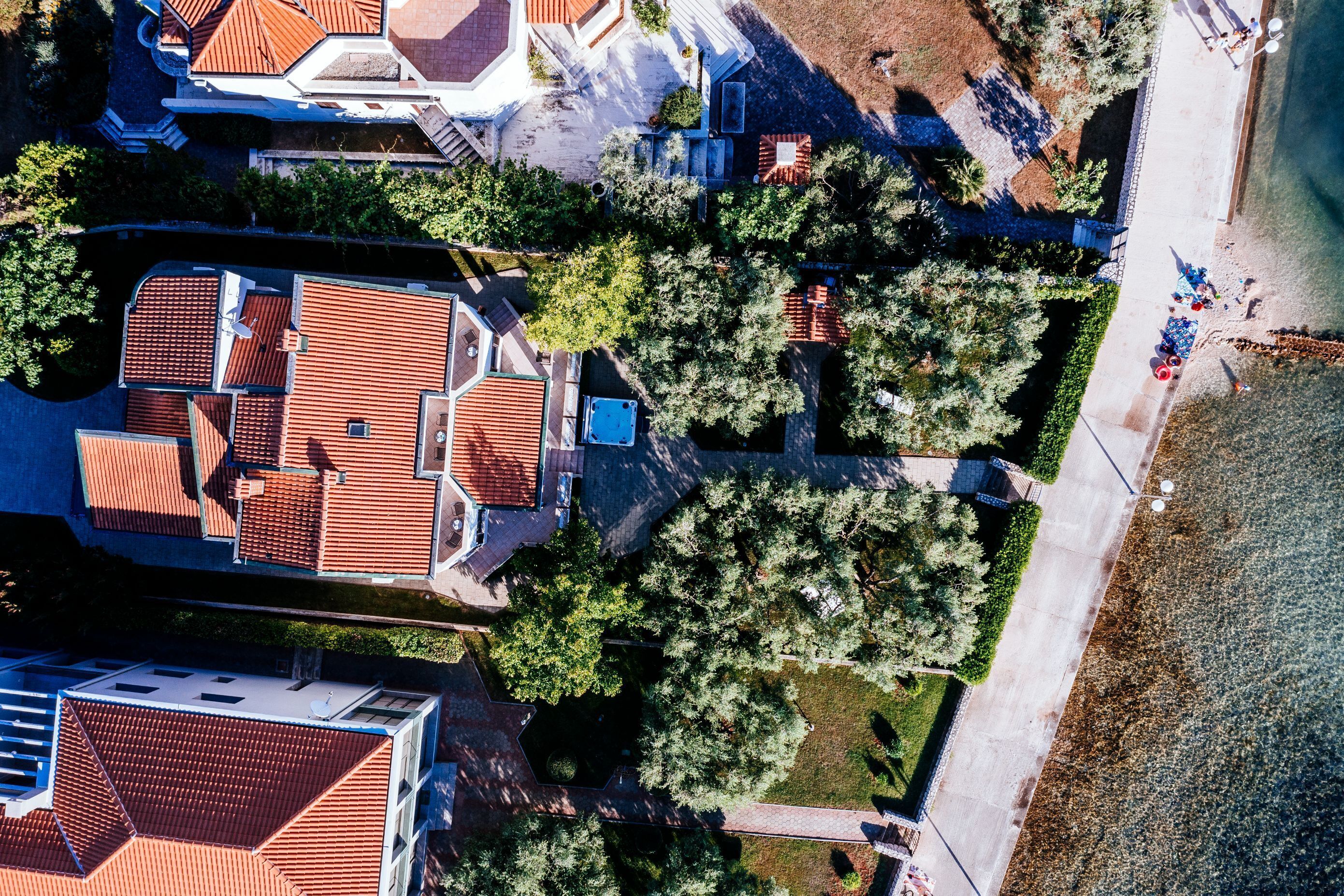An aerial view of a residential area with multiple houses, a paved pathway, and a body of water.