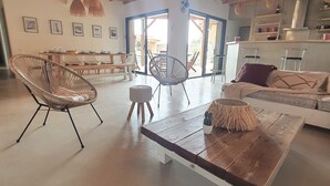 Ein geräumiger Wohnbereich mit Holzboden, einem Esstisch für sechs Personen und einer Couch mit Kissen.