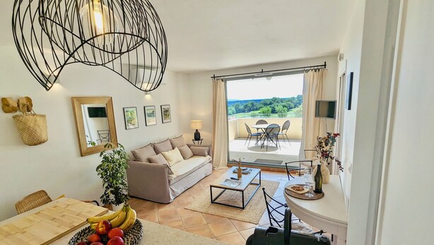 Un salon comprenant un canapé, une table à manger et un balcon aménagé avec du mobilier d’extérieur.