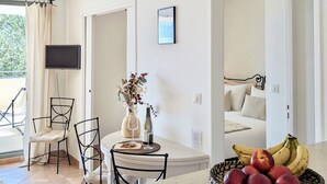 Un salon moderne avec un coin repas, comprenant une table ronde, des chaises, un luminaire suspendu et un panier de fruits.