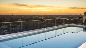 A rooftop pool with a cityscape view during sunset. - Asuncion Rent Suites Santa Teresa (Asunción)