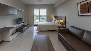 A modern hotel room with a bed, a sofa, a TV, and a desk. - Asuncion Rent Suites Santa Teresa (Asunción)