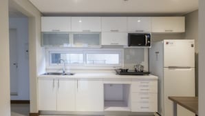 A modern kitchen with white cabinets, a microwave, a refrigerator, and a window above the sink. - Asuncion Rent Suites Santa Teresa (Asunción)