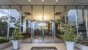 A hotel entrance with a revolving door, potted plants, and a doormat with "The One." written on it. - Asuncion Rent Suites Santa Teresa (Asunción)