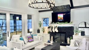 Un salon moderne avec une cheminée, des canapés blancs et un grand téléviseur fixé au mur.