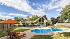 En trädgård med pool, en täckt uteplats och ett hus.