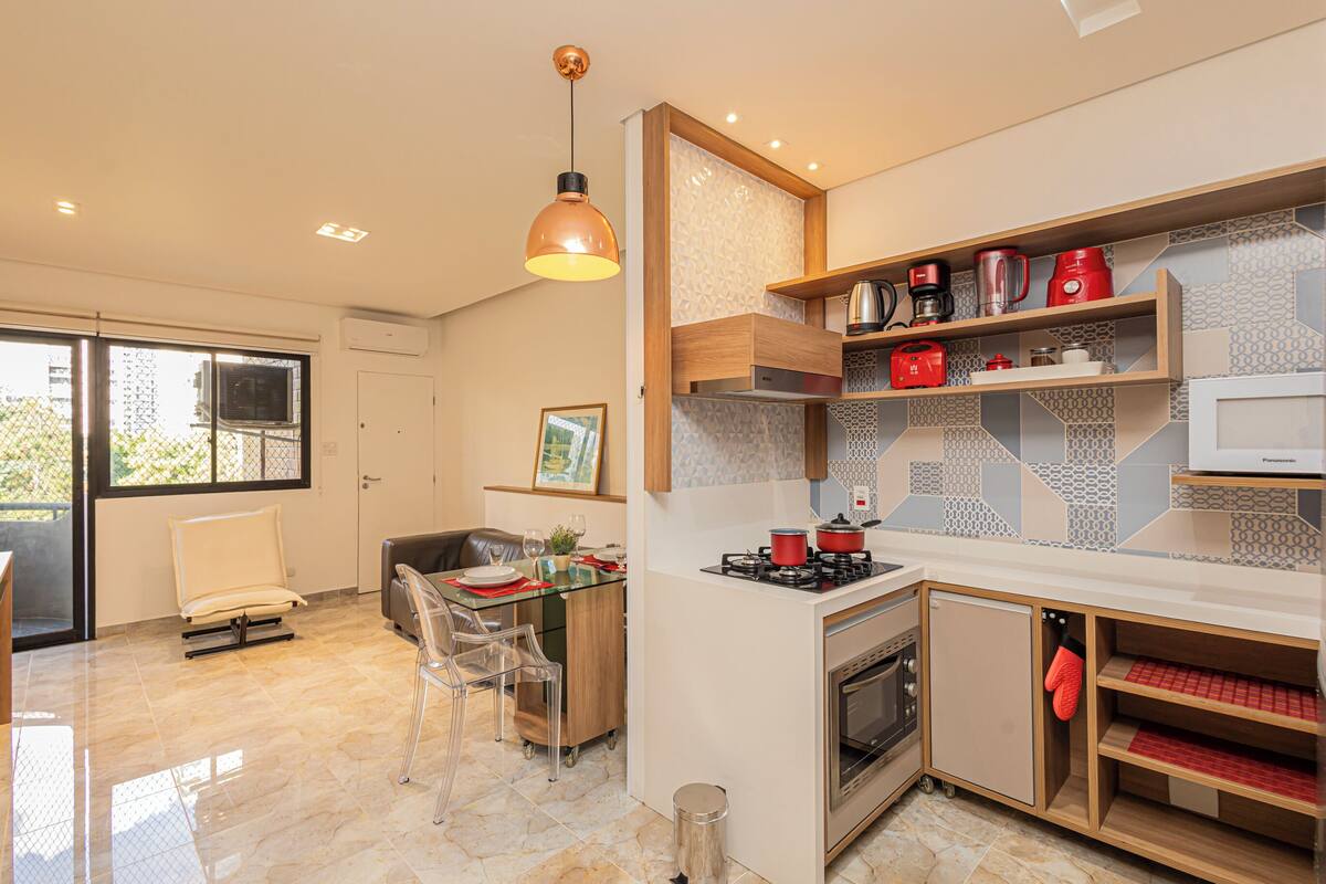 Een moderne keuken met een gasfornuis, een koffieapparaat en een magnetron. Er is een eethoek met een tafel en stoelen.