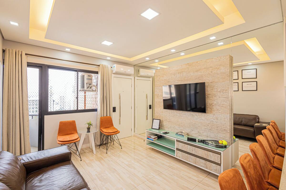 Een moderne woonkamer met een bank, stoelen, een televisie en een glazen salontafel.