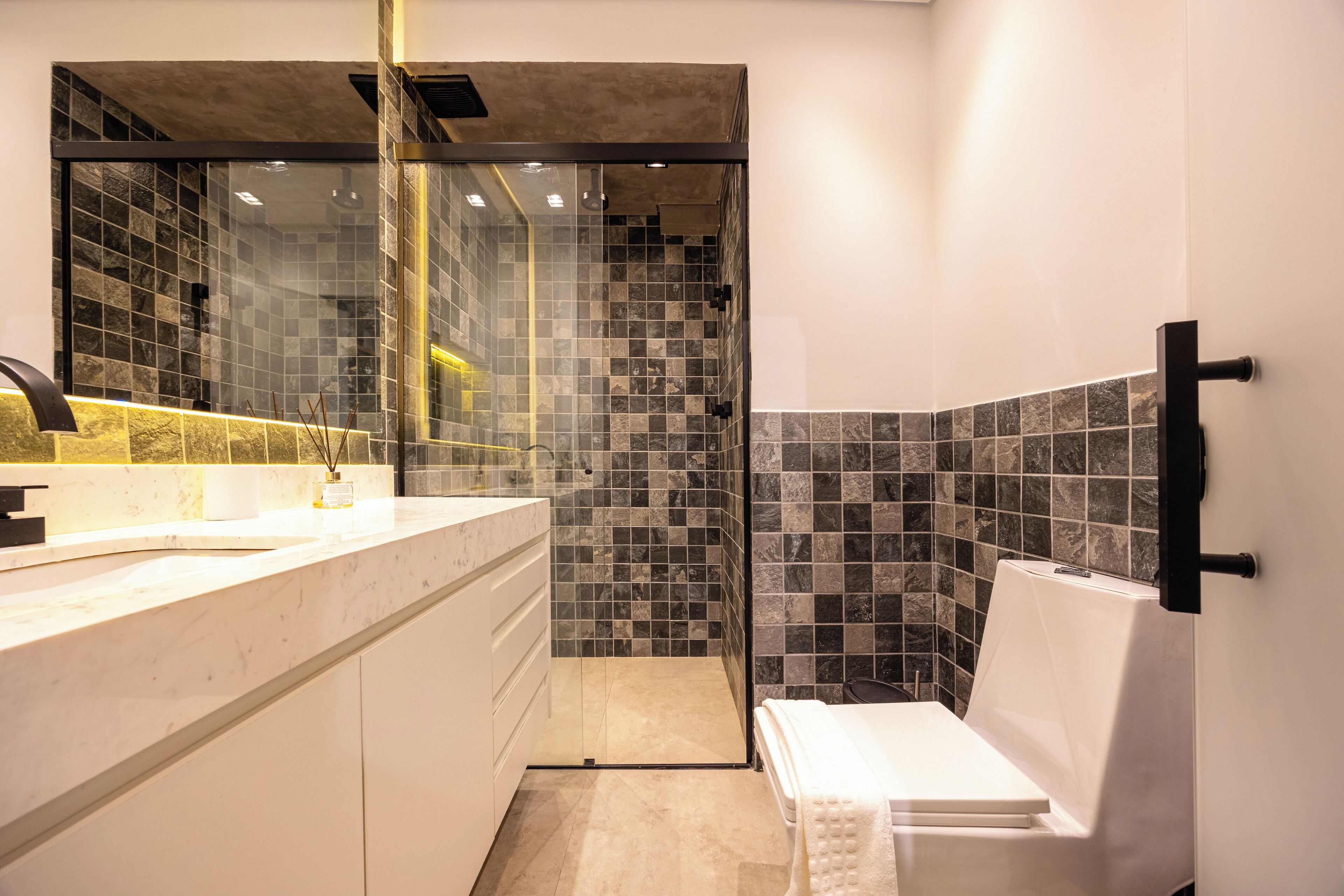 Un bany modern amb dutxa separada per vidre, un lavabo blanc i un vàter.