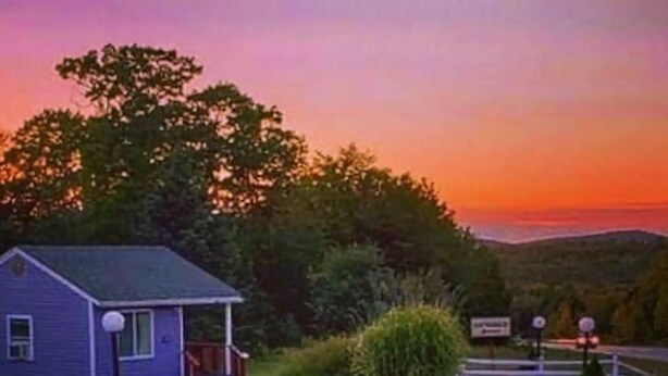 Una casita con porche, rodeada de vegetación y una vista panorámica.