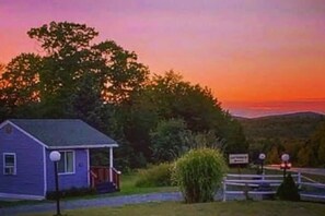 Una casita con porche, rodeada de vegetación y una vista panorámica.