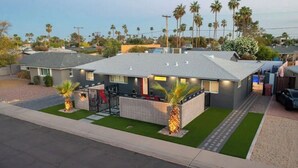 Une maison moderne à deux étages, dotée d’un toit plat, d’un patio couvert et d’un petit jardin clos.