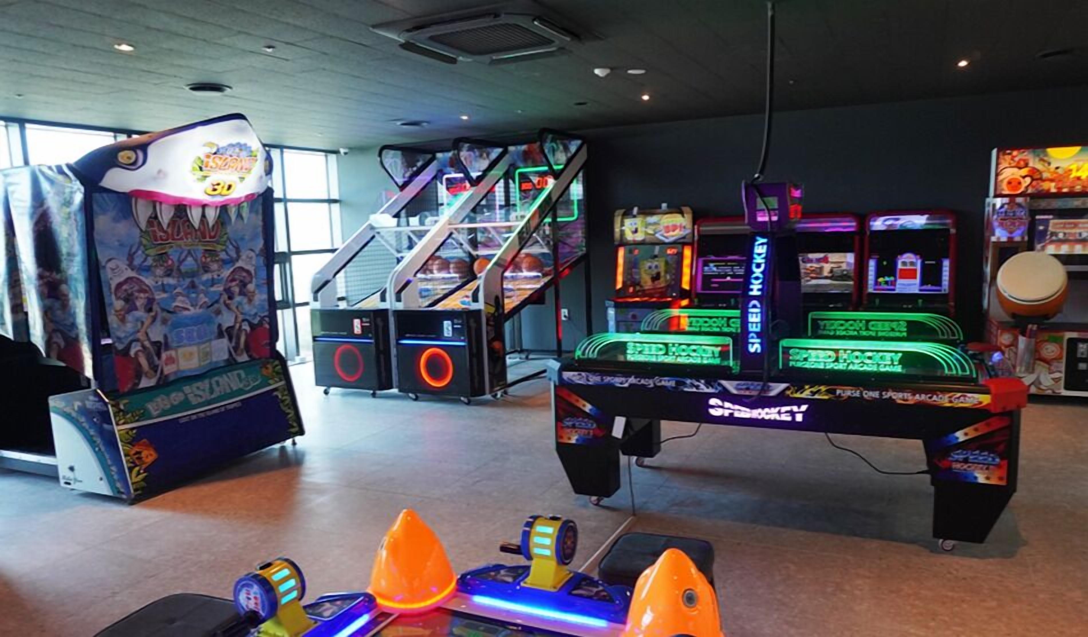 An indoor arcade with various gaming machines, including a speed hockey game and a claw machine.