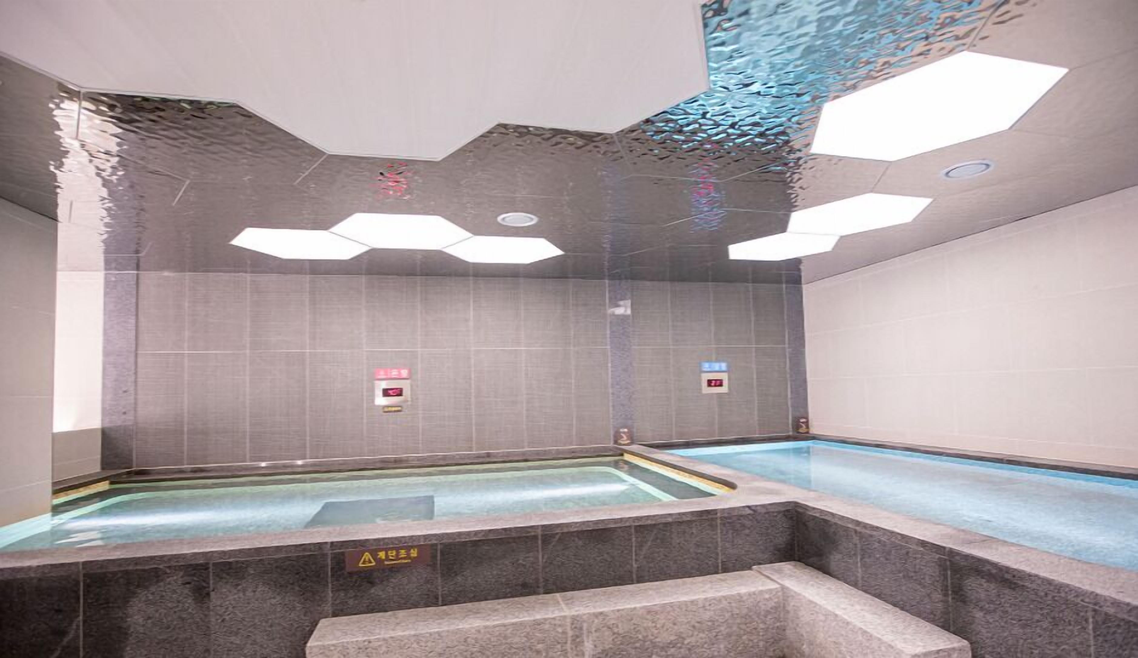 Una piscina interior moderna con diseño geométrico en el techo y paredes de azulejos.