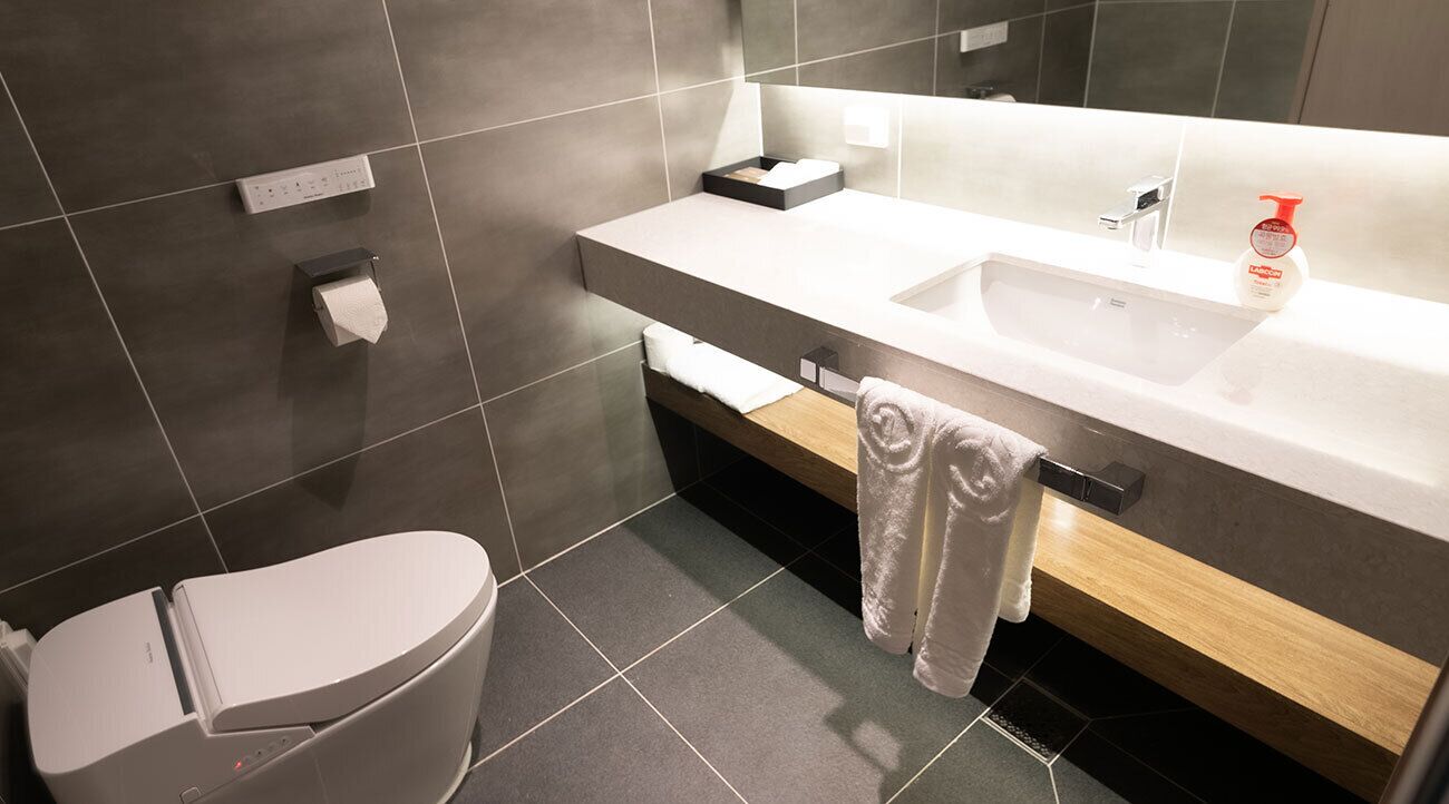 Ein modernes Badezimmer mit Toilette, Waschbecken und Handtuchhalter.
