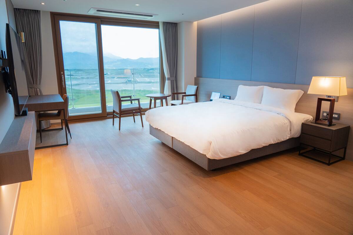 Una habitación de hotel moderna con una cama grande, un escritorio y una silla.