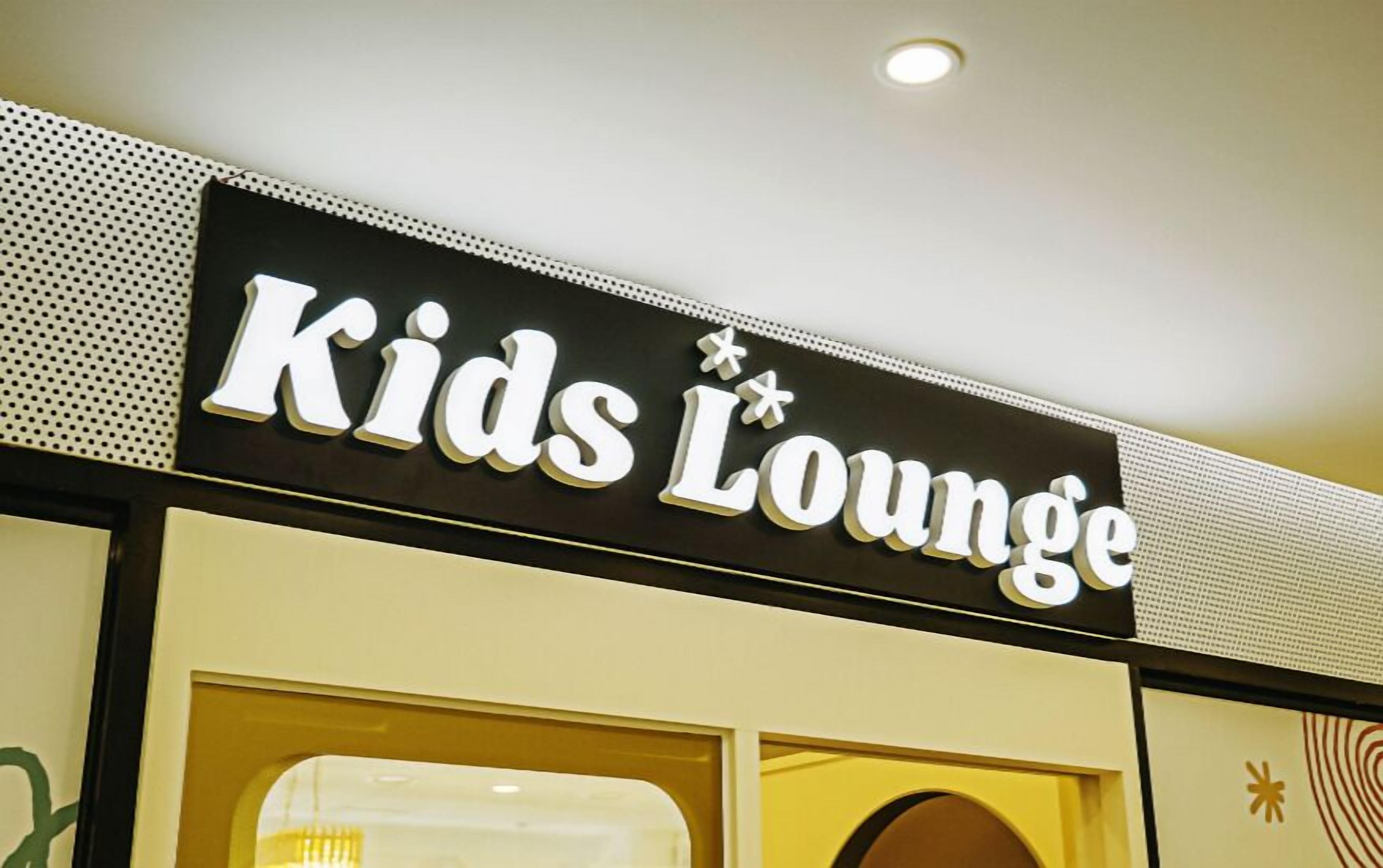 Letrero que dice 'Kids Lounge', con fondo negro y letras blancas.