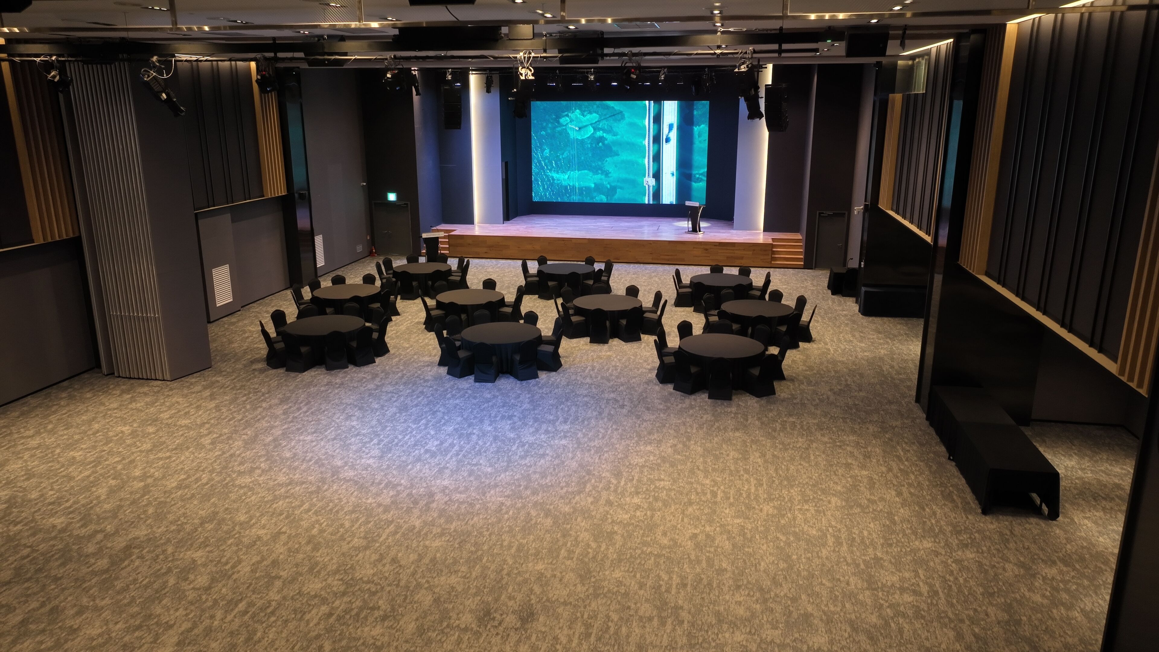 Un salón de conferencias con varias mesas y sillas dispuestas para una reunión.