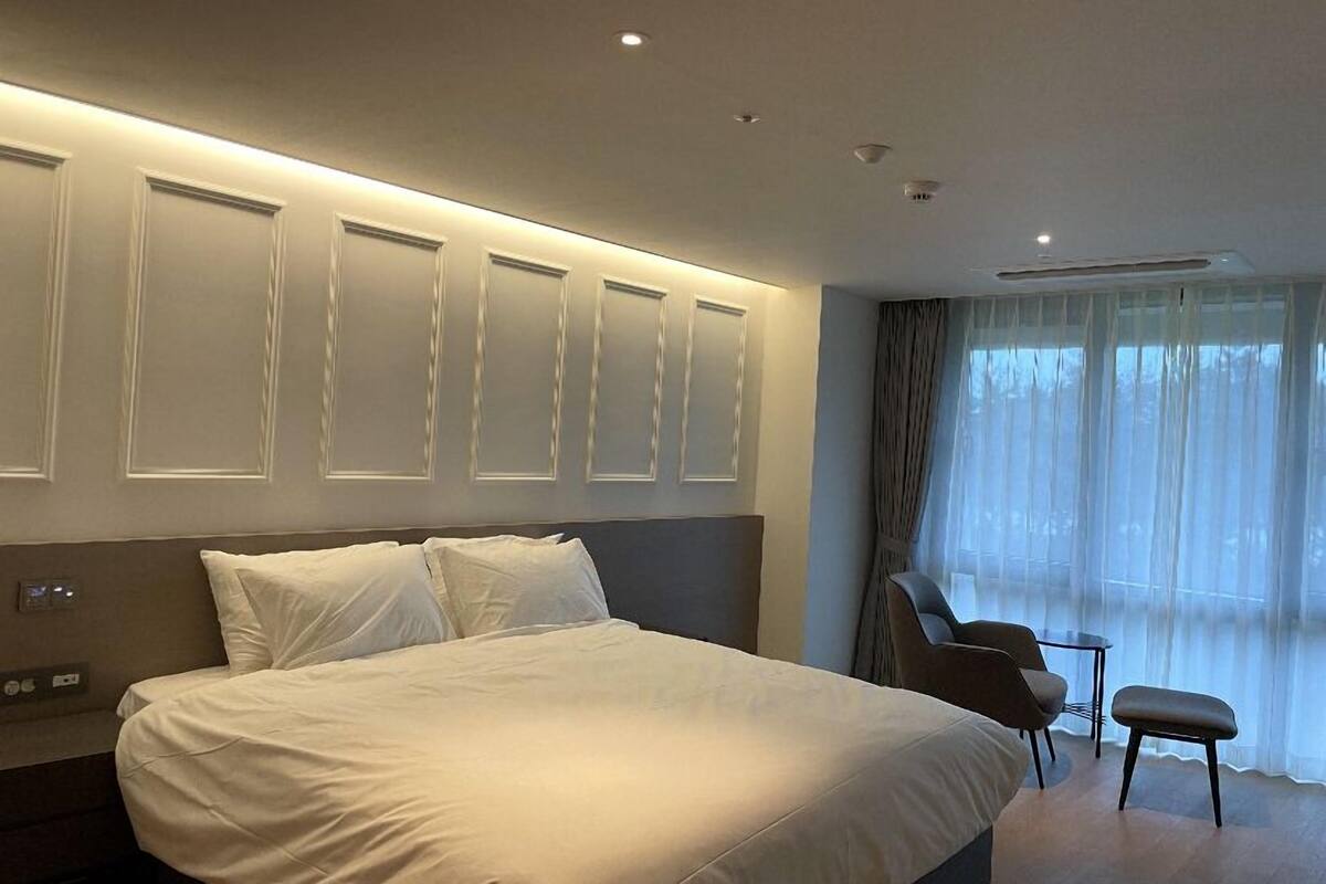 Una habitación de hotel moderna con una cama grande, un escritorio y una silla.