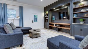 Een moderne woonkamer met een hoekbank, een salontafel en inbouwkasten met decoratieve objecten.