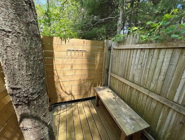 Guests can sit on the outdoor bench surrounded by a fence and a tree.