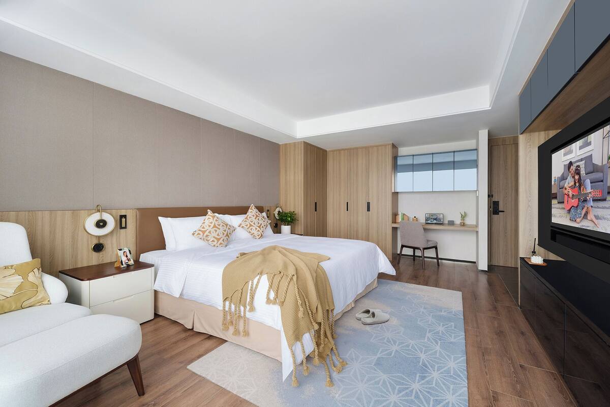 Une chambre à coucher moderne, comprenant un lit, des tables de chevet, un bureau et un téléviseur.