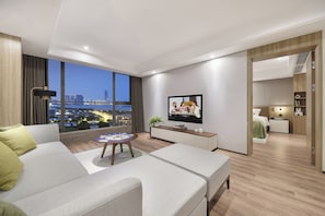 A modern living room with a sofa, a coffee table, a TV, and a city view. - Somerset Suzhou Bay Suzhou (Suzhou)