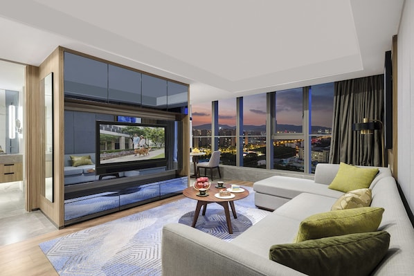 A modern living room with a large TV, a sofa, a coffee table, and a city view. - Somerset Suzhou Bay Suzhou (Suzhou)