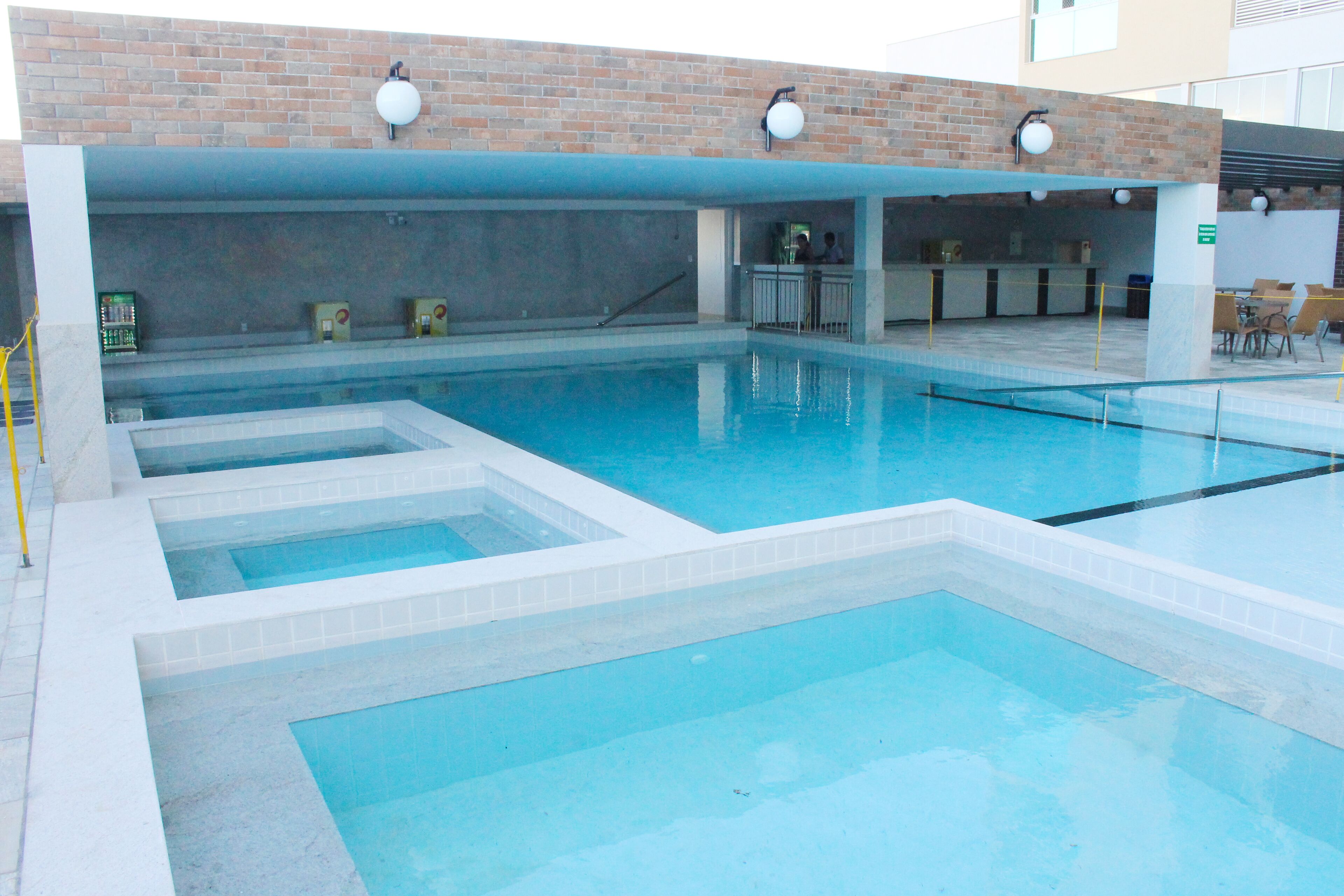 Une piscine avec plusieurs couloirs, un espace d’accueil et un mur en briques.