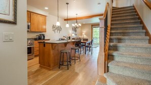 A spacious kitchen with wooden cabinets, a central island with stools, and a staircase leading to another level. - Great Location Near Pool with Suncadia Pool Access (Cle Elum)