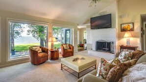 A spacious living room with a fireplace, large windows, and a ceiling fan. - Family Friendly Lakefront Luxury, Private Water trampoline, arcade, BYOB boat (Livingston)