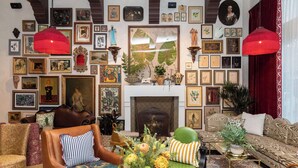 A cozy living room with a fireplace, multiple framed artworks, and a variety of seating options. - Graduate by Hilton Palo Alto (Palo Alto)