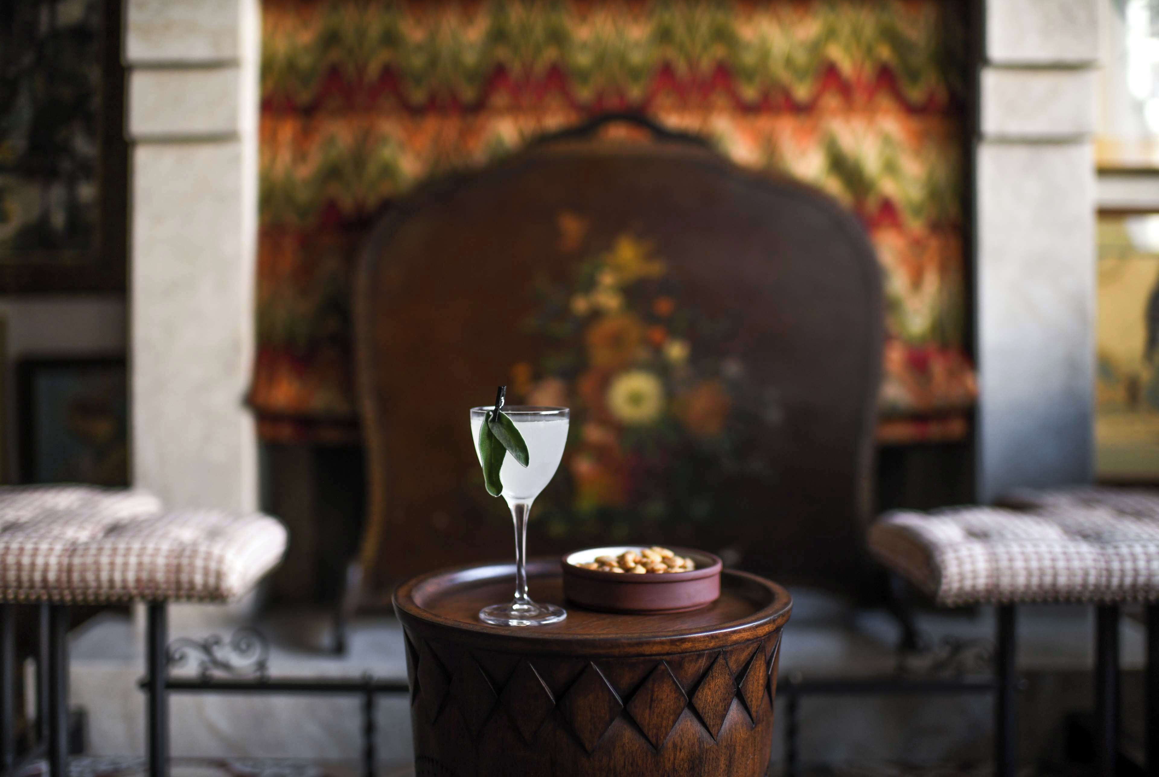 A bar area with a cocktail glass, a bowl of nuts, and a chair.