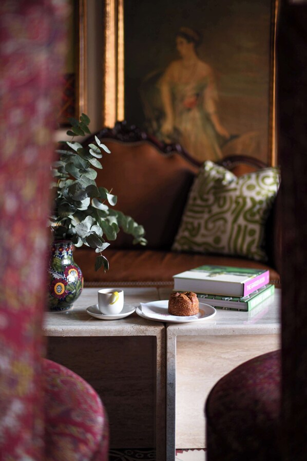 A cozy living room with a sofa, a coffee table, a vase with a plant, and a painting on the wall.