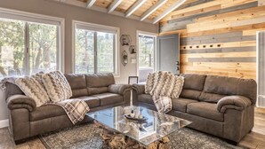 Un salon chaleureux avec deux canapés en cuir, une table basse en verre et un plafond en bois.