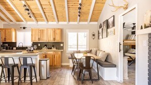 Une cuisine moderne avec des meubles en bois, un coin repas doté d’une banquette et un espace détente avec une banquette intégrée.