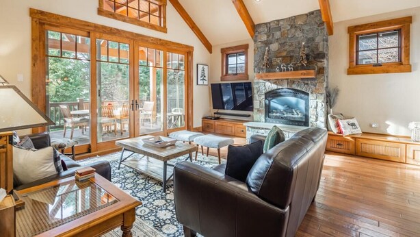 A spacious living room with a stone fireplace, wooden beams, and large windows. - Central Location w/ Suncadia Pool Access (Cle Elum)