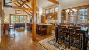 A spacious kitchen with wooden beams, a large island, and a dining area with chairs and a rug. - Central Location w/ Suncadia Pool Access (Cle Elum)