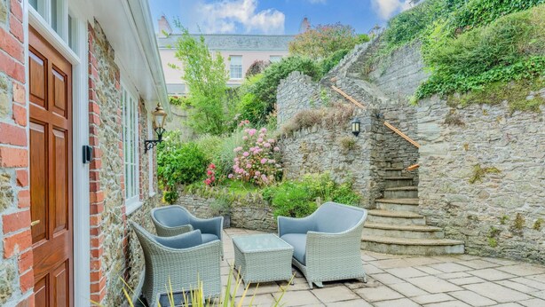 Eine Terrasse mit Korbmöbeln, einer Steinmauer und einer Treppe.